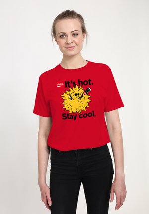 Rode katoenen t-shirt met een afbeelding van een gele leeuw met een zonnebril en een drankje, tekst leest "Het is heet. Blijf cool." Korte mouwen.