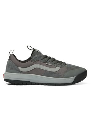 Zapatilla gris de ante y tela con suela de goma, diseño de cordones y etiqueta de logo en el lateral, que presenta una forma aerodinámica y una pestaña de tiro.
