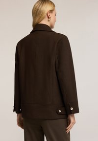Brązowa wełniana kurtka z ustrukturyzowanym kołnierzem i detalami szwu z tyłu. Posiada złote guziki na mankietach i u dołu, które dodają jej uroku.
