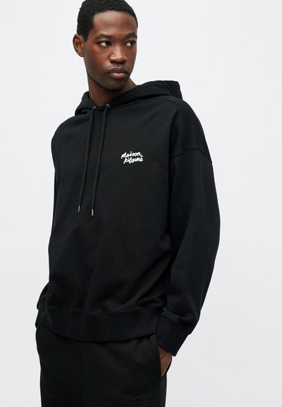 Hanorac negru din bumbac, cu un buzunar tip kangaroo în față, croială obișnuită, glugă cu șnur și logo brodat alb pe piept.