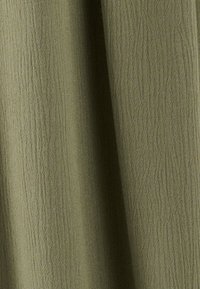 Tela verde oliva con una superficie texturizada y arrugada, mostrando sutiles variaciones en el tono y una apariencia suave y ligera.