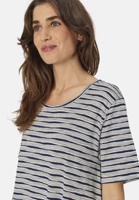 Top de manga corta a rayas en azul marino y blanco, con un cuello redondo y un corte holgado, fabricado en una suave textura de algodón.