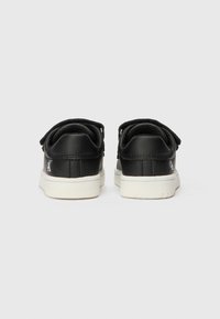 Sapatos de couro pretos com solas de borracha branca. Apresentam um salto arredondado e atacadores pretos. Logótipo estampado na lateral; painéis texturizados na parte de trás.