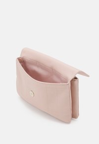 Ljusrosa kuvertväska tillverkad av slätt material, med ett guldspänne, inredning som är fodrad med "Calvin Klein"-logotyp och subtila sömdetaljer.
