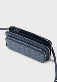 Modra denarnica z zadrgo iz teksturirane tkanine z logotipom, z več predelki in snemljivim trakom. Srebrni kovinski dodatki.