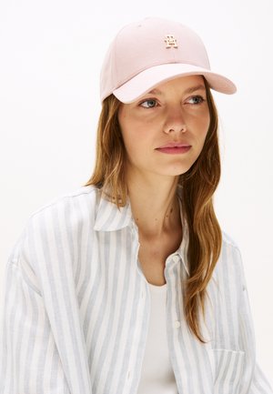 Roze baseballpet van katoen met een gebogen klep en een goudkleurig logo aan de voorkant. De achtergrond is effen wit.