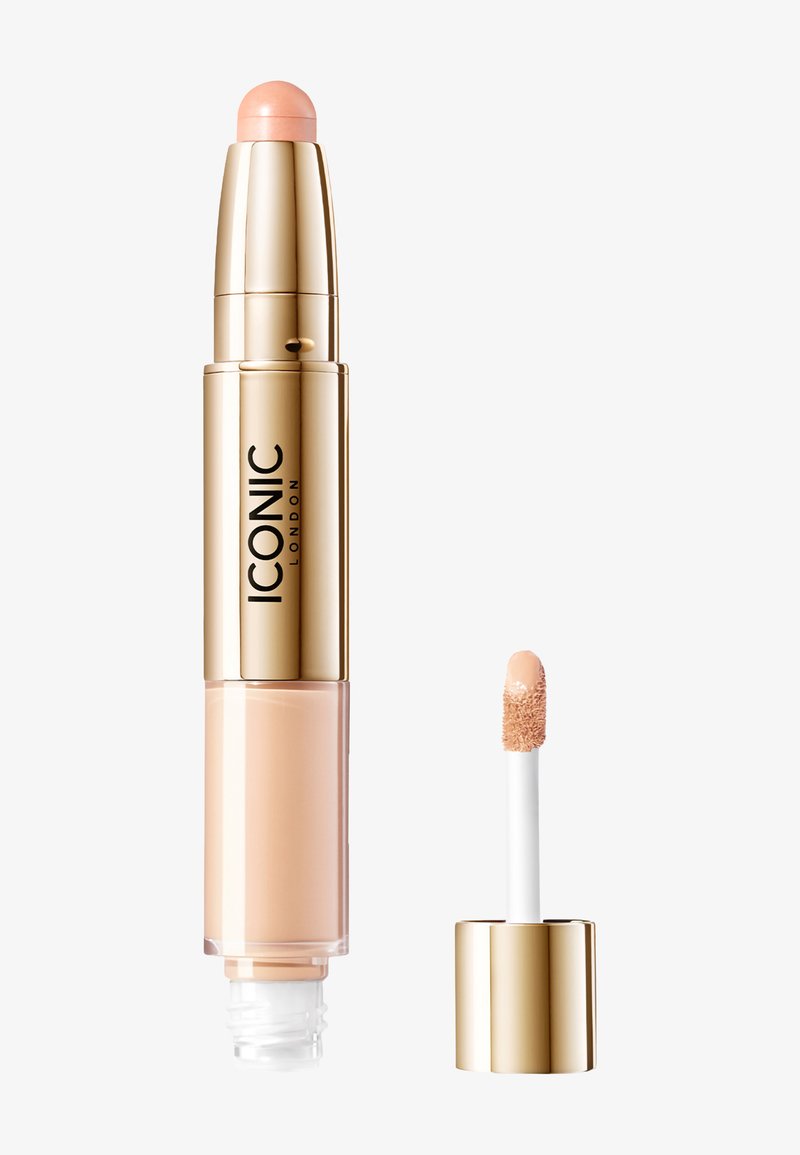To-delt kosmetisk produkt: gullfarget sylinderformet beholder med en lys ferskenfarget kremstift på toppen; ved siden av er en applikator med hvit tupp med flytende concealer.