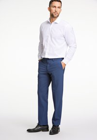 Weißes Hemd mit Knöpfen, blaue Hose und schwarze Lederschuhe. Figurbetontes Design mit glatter Textur und maßgeschneidertem Schnitt.