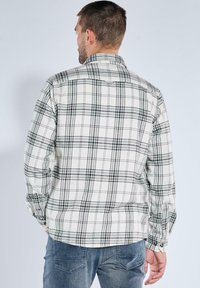 Karierte Flanellhemd in Schwarz und Weiß mit einem Button-Down-Kragen, langen Ärmeln und entspannter Passform. Verfügt über ein schachbrettartiges Muster und knöpfbare Manschetten.