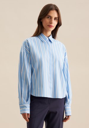 Camicia azzurra chiara con colletto e strisce verticali bianche, maniche lunghe e dettagli abbinati ai polsini. Realizzata in tessuto morbido con una vestibilità rilassata.