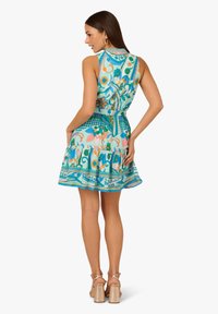 Un vestito senza maniche di colore turchese con motivi floreali e geometrici, che presenta un corpetto aderente, una gonna ampia e un orlo a strati con merletto.