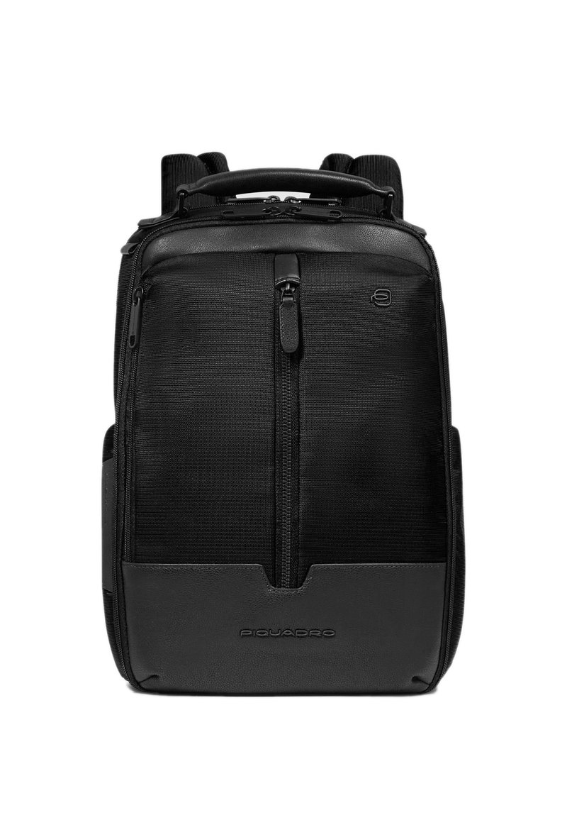 Mochila negra con cuerpo de tela texturizada y detalles de cuero liso, con asa superior, correas ajustables y bolsillos frontales con cremallera.