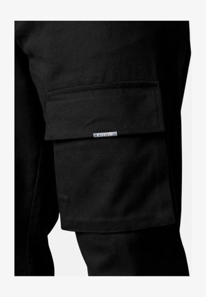 Black cargo pants featuring a side pocket and a silver brand tag. Strong, sturdy fabric with a smooth texture and clean stitching.