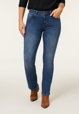 Blauwe denim jeans met een rechte pasvorm, vijf-pocket ontwerp en subtiele vervaging. Gecombineerd met bruine enkellaarzen.