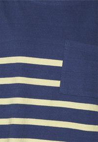 Tecido azul marinho riscado com riscas amarelas horizontais e um bolso aplicador. O material é macio e canelado, criando uma aparência texturada.