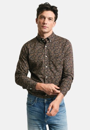 Tamsus marškiniai su paisley raštu, kuriame dominuoja raudonos, mėlynos ir kremų spalvos; ilgomis rankovėmis ir smailiu apykakle.
