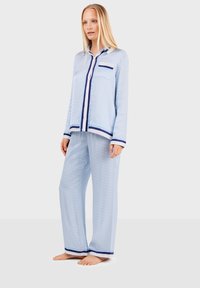 Light blue pajama set in a geometric pattern, featuring a buttoned shirt with navy accents and matching pants with a cuffed hem.