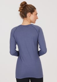 Langärmliges Oberteil in einem gedämpften Blau, mit geripptem Textur, taillierter Passform und Raglanärmeln. Glatte Oberfläche mit einem runden Halsausschnitt.