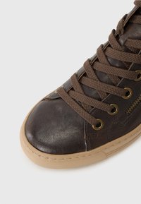 Baskets montantes marron avec tige en cuir, finition texturée, bout rond, lacets marron et œillets dorés, dotées d'une semelle en caoutchouc beige.