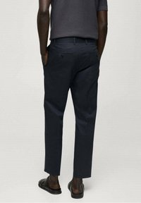 Tmavě modré kalhoty z lehké látky, s rovný střih, bočními a zadními kapsami a jednoduchým designem.