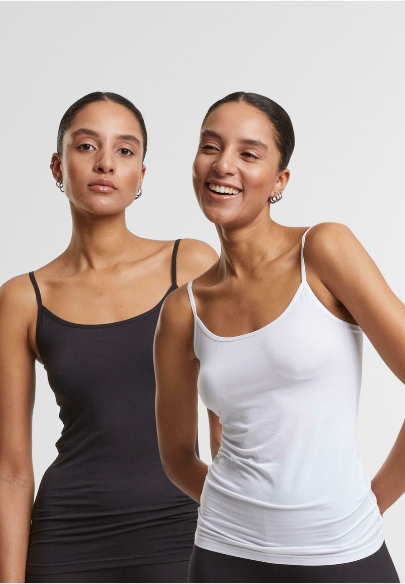 Two fitted camisole tops, one black and one white, with thin straps and a soft, stretchy fabric. Smooth texture with a rounded neckline.