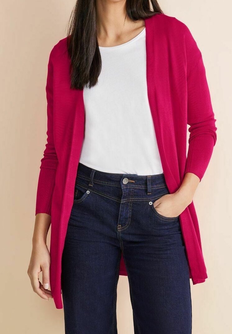 Fuchsieový kardigan s dlouhými rukávy, otevřený design, lehká pletenina, kombinovaný s bílým tričkem a tmavě modrými džíny.