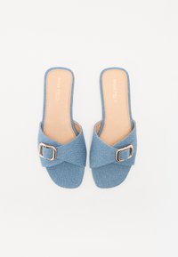Blå denim slidesandaler med kryssdesign, som har et metallisk spenneaktillegg og en lysbrun såle. Flat såle og glatt tekstur.