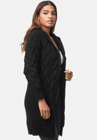 Cardigan lungo nero lavorato a maglia con un motivo a treccia testurizzato, apertura frontale e cappuccio. Le maniche a coste e l'orlo aggiungono interesse visivo.