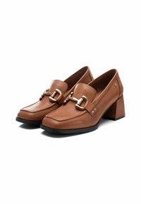 Mocasines de cuero marrón con tacón, de punta cuadrada, con detalles de hardware dorado y tachuelas decorativas en la parte trasera. Diseño de tacón de bloque grueso.