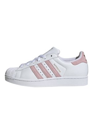 Baskets basses blanches avec des rayures rose clair, fermeture à lacets, bout shell et étiquette "SUPERSTAR" sur le côté.