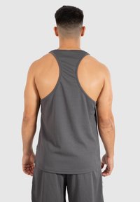 Grijs spierhemd met een geribbelde textuur, voorzien van een racerback ontwerp. Gecombineerd met bijpassende shorts, geschikt voor sportkleding.
