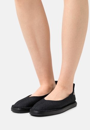 Sorte slip-on sko lavet af tekstureret stof, med lav profil, rund tå og en holdbar gummisål.