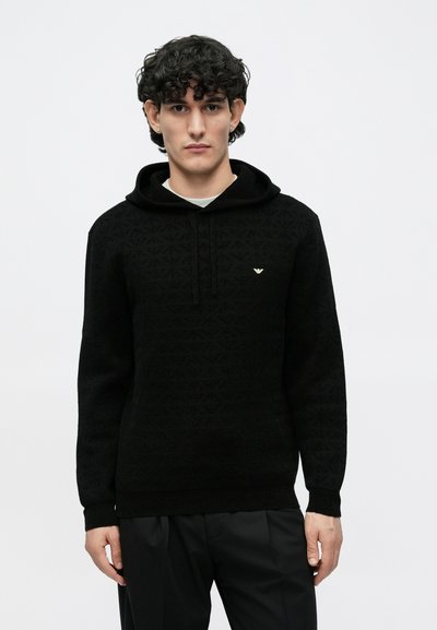 Camisola preta com capuz feita em tecido texturizado, apresentando um padrão subtil e um logótipo dourado no peito. Corte descontraído com capuz ajustável por cordão.