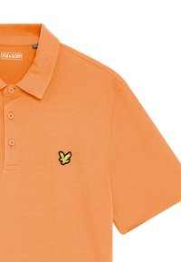 Orange polo shirt lavet af glat bomuldsstof, med en to-knaps knaplukning og et sort og gult broderet logo på venstre bryst.