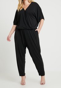 Czarny kombinezon z dekoltem w serek, krótkimi rękawami i luźnym krojem. Posiada marszczoną talię i zwężane nogawki, wykonany z miękkiego, elastycznego materiału.