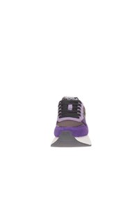 Zapatilla deportiva púrpura y negra con parte superior de ante, cordones destacados, cuello acolchado y suela gris contrastante. Vista frontal.