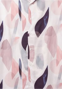 Blouse blanche ornée de formes abstraites en rose, gris et marine. Comprend une fermeture boutonnée à l'avant et un tissu léger et lisse.