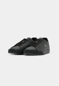 Sneaker neri con tomaia in pelle liscia, punta tonda, design con lacci, suola in gomma e un accento logo discreto sul lato.