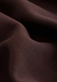 Tejido de punto marrón con una textura suave, que presenta un fino tejido en diagonal y sutiles variaciones en la tonalidad. Suave y cae de manera natural.