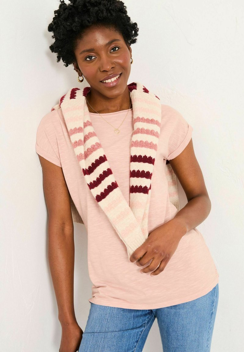 Light pink short-sleeve shirt under a beige and burgundy striped scarf. Blue jeans and a heart necklace complete the look.