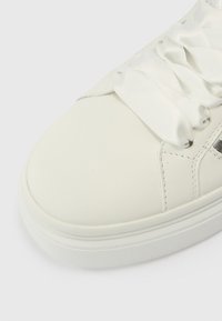 Λευκό δερμάτινο αθλητικό παπούτσι με ομαλή επιφάνεια, στρογγυλεμένη μύτη και σατέν κορδόνια. Διαθέτει υφασμένο καουτσούκ στη σόλα και διακριτικές ραφές ως διακοσμητικά στοιχεία.