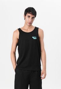 Fekete pamut ujjatlan póló, lekerekített nyakkivágással, bal mellen türkiz "Tommy Jeans" logóval. Kényelmes, laza szabású.