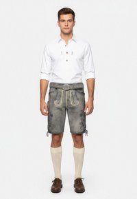 Graue Lederhosen mit gelben Akzenten und gestickten Details, kombiniert mit einem weißen Hemd, knielangen cremefarbenen Socken und dunklen Schuhen.