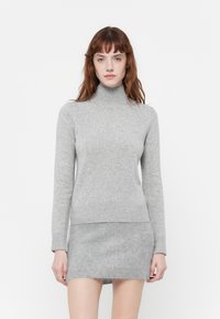 Siv pulover s turtleneck iz pletenine z dolgimi rokavi, mehkega otipa in prilegajočega dizajna, vparen z ujemajočim sivim mini krilom.