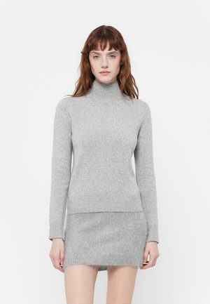 Grå strikket turtleneck genser med lange ermer, myk tekstur og en tettsittende design, kombinert med et matchende grått miniskjørt.