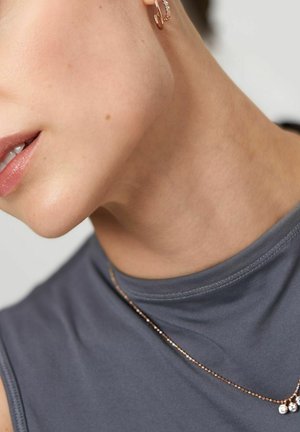 Graues ärmelloses Oberteil mit einer glatten Textur, begleitet von einer zarten Halskette aus roségold mit kleinen, runden, klaren Akzenten.