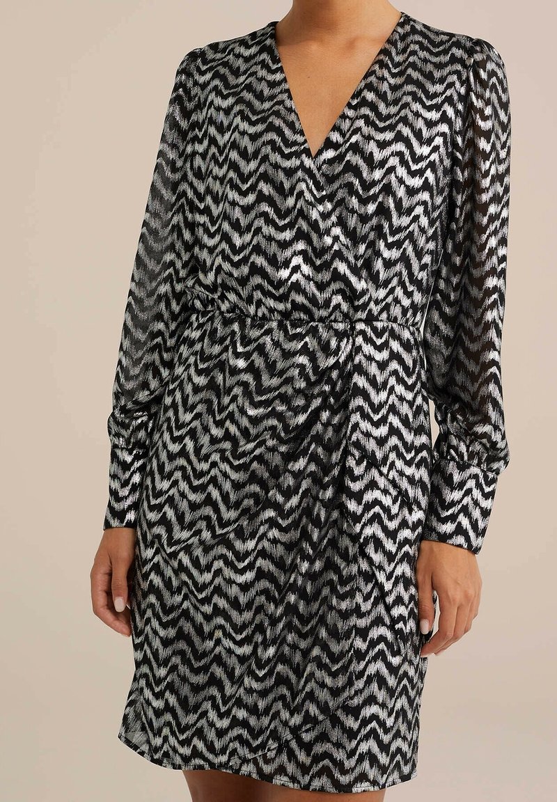 Black and white zigzag patterned dress with a v-neck, long sleeves, and a cinched waist, made from lightweight, semi-sheer fabric.