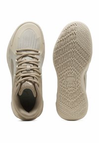 Beige sportsko med en tekstureret mesh-overdel, rund tå og snørrebånd; med en mønstret gummisål for godt greb.