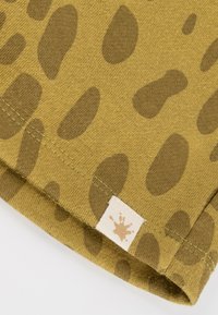 Baumwollhemd mit khakifarbenem Hintergrund und unregelmäßigen braunen Leopardenflecken. Verfügt über einen genähten Saum und ein Etikett mit einem Spritzgrafik.