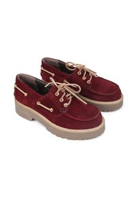 Zamszowe buty żeglarskie w kolorze burgundowym z beżowymi sznurówkami i złotymi oczkami. Posiadają grubą, beżową gumową podeszwę o fakturowanym wykończeniu.